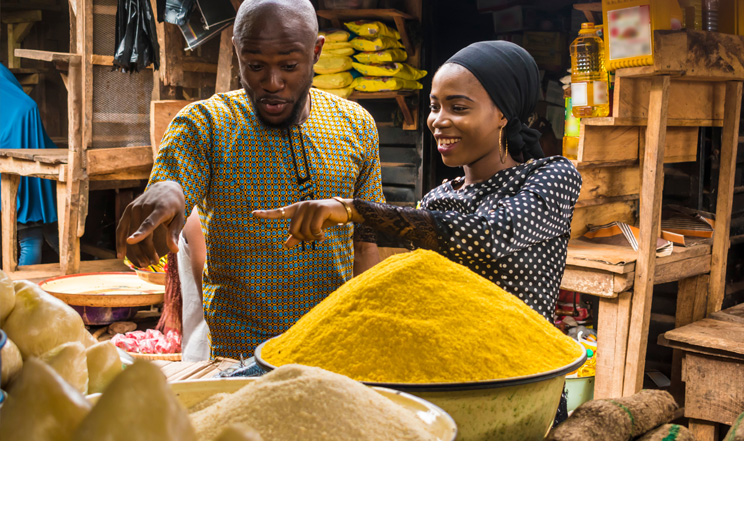 Man and woman smiling and pointing to different kinds of spices